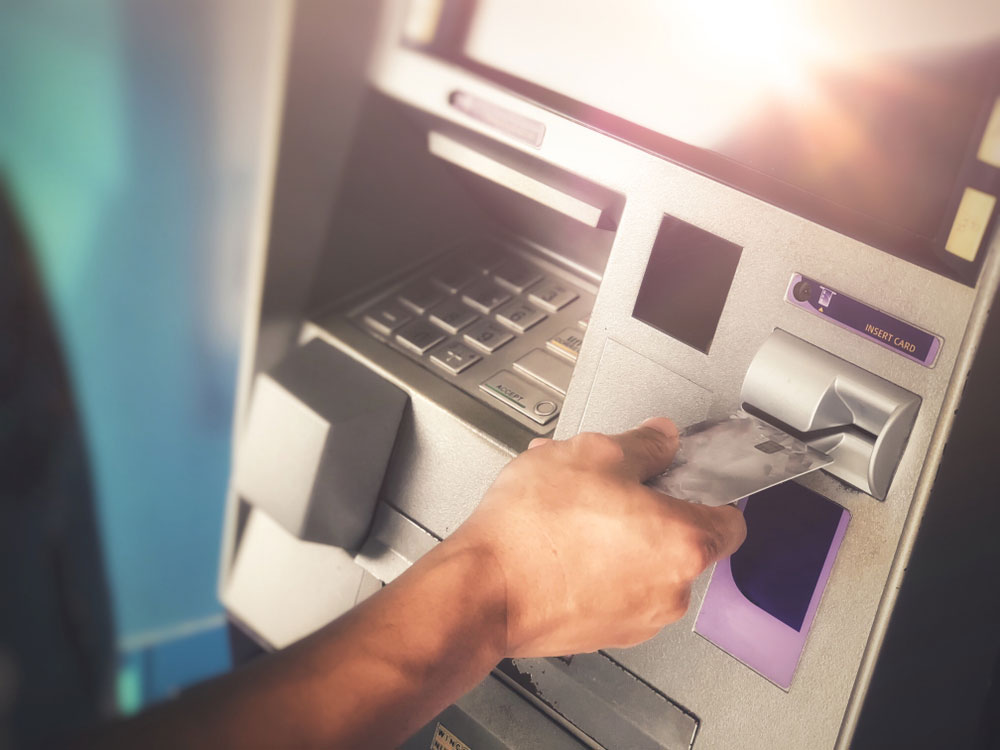 A hand inserting a card into an ATM machine.