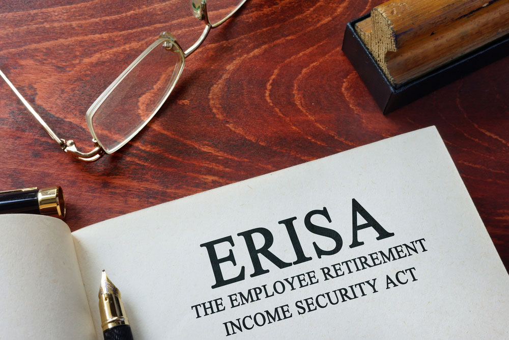 An ERISA document on a table with reading glasses and a pen.
